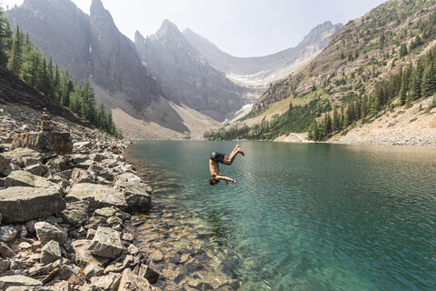 Seitenansicht eines Mannes, der im See vor den Bergen des Banff National Park taucht, lizenzfreies Stockfoto