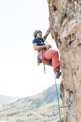 Low angle view of female hiker using rope while climbing on mountain - CAVF51828