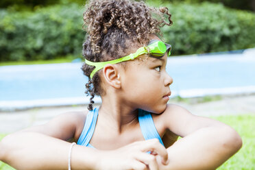 Thoughtful girl with swimming goggles looking away against lake - CAVF51834