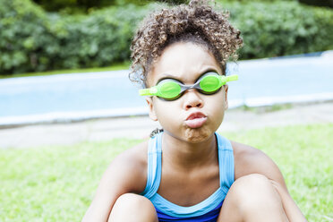 Verspieltes Mädchen mit Schwimmbrille am See, das sich kräuselt - CAVF51835