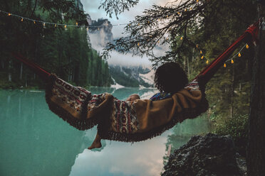 Young woman resting in hammock against lake - CAVF51840