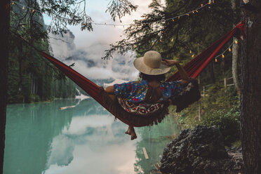 Young woman looking at view while sitting in hammock over lake - CAVF51841