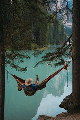 High angle view of young woman resting in hammock against lake - CAVF51842