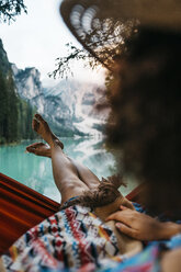 Close-up of young woman resting in hammock against lake - CAVF51843