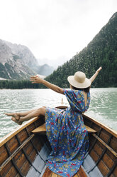 Happy woman enjoying rowboat riding over lake against mountains - CAVF51852