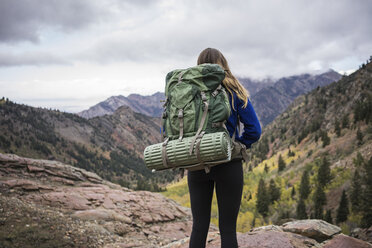 Rückansicht einer Wanderin mit Rucksack auf einem Berg vor bewölktem Himmel - CAVF51857