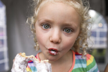 Porträt eines süßen Mädchens, das beim Essen eines Donuts ein Gesicht macht - CAVF51867