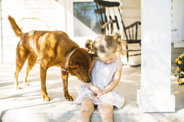Hund spielt mit Mädchen auf Veranda - CAVF51877