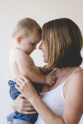 Mutter und hemdsärmeliger Sohn berühren sich an der Stirn vor weißem Hintergrund - CAVF51931
