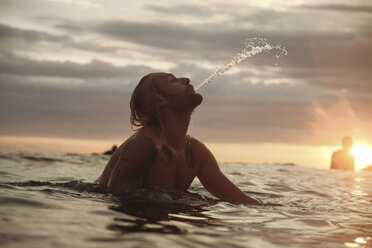 Silhouette Mann spritzt Wasser beim Surfen auf dem Meer gegen den Himmel bei Sonnenuntergang - CAVF51940