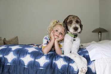 Porträt eines Mädchens mit Hund auf dem Bett liegend an der Wand - CAVF51968