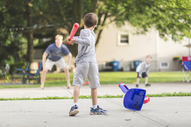 Rückansicht eines Jungen, der mit Vater und Bruder im Park Baseball spielt - CAVF52008