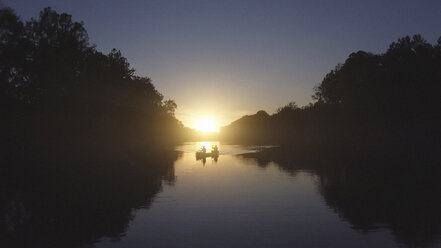 Vater und Sohn beim Bootfahren auf dem See bei Sonnenuntergang - CAVF52019