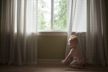 Hemdloser kleiner Junge kniet auf dem Boden am Fenster - CAVF52028