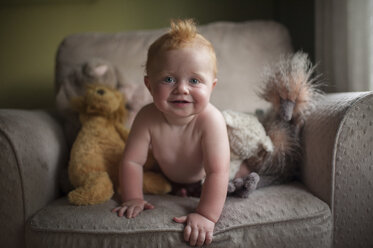 Porträt eines niedlichen kleinen Jungen ohne Hemd auf einem Sessel zu Hause - CAVF52030