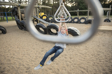 High angle view of boy hanging on monkey bars at playground - CAVF52082