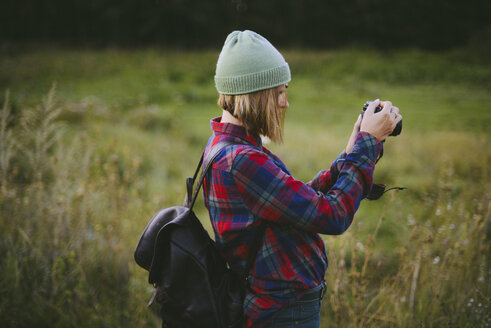 Seitenansicht einer Frau, die auf einer Wiese stehend fotografiert - CAVF52120