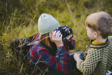 Mutter fotografiert Sohn mit Kamera auf dem Feld - CAVF52131