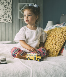 Thoughtful girl with toys sitting on bed - CAVF52144