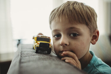 Porträt eines Jungen, der zu Hause mit einem Spielzeuglastwagen spielt - CAVF52170