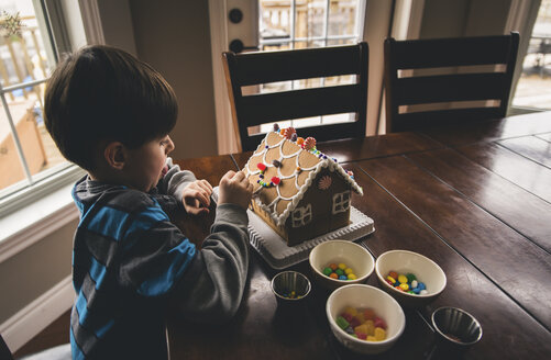 Hohe Winkel Ansicht des Jungen machen Lebkuchenhaus auf Holztisch während Weihnachten zu Hause - CAVF52232