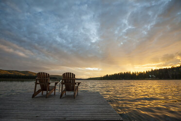 Chairs on pier by Lac Le Jeune lake at Paul Lake Provincial Park against sky during sunset - CAVF52258