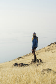 Side view of woman looking at sea while standing on rock against sky - CAVF52312