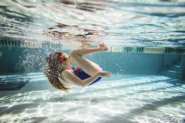Verspieltes Mädchen schwimmt unter Wasser im Pool - CAVF52326