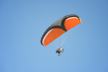 Low angle view of young man motor paragliding against clear sky - CAVF52330