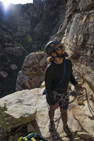 Hoher Blickwinkel eines Bergsteigers, der auf einem Berg stehend nach oben schaut, lizenzfreies Stockfoto