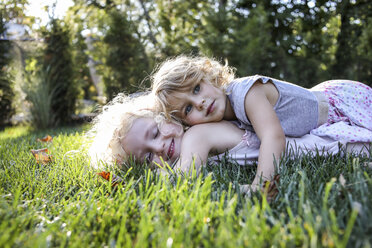 Sisters lying on grassy field at park - CAVF52339