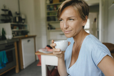 Lächelnde Frau zu Hause trinkt eine Tasse Kaffee - KNSF05041