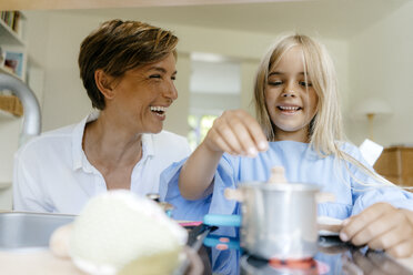 Glückliche Mutter und Tochter spielen zu Hause mit einer Spielzeugküche - KNSF05045
