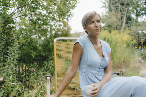 Woman sitting in garden with cup of coffee - KNSF05061