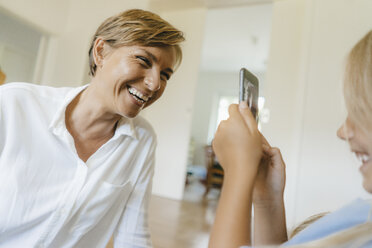 Daughter taking smartphone picture of happy mother - KNSF05062