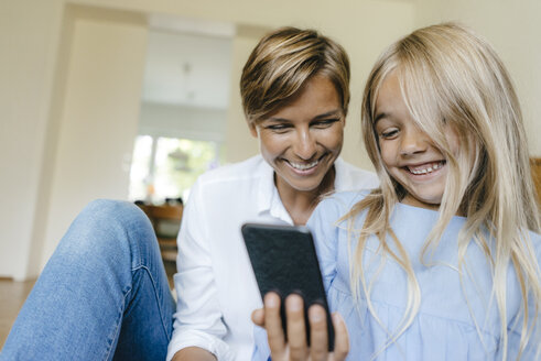 Glückliche Mutter und Tochter schauen gemeinsam auf ihr Smartphone - KNSF05063