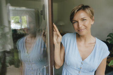 Portrait of smiling woman at French window - KNSF05081