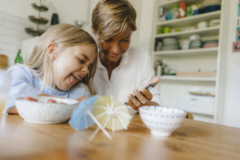 Glückliche Mutter und Tochter haben Spaß am Tisch zu Hause, lizenzfreies Stockfoto