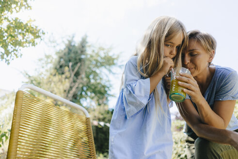 Mutter und Tochter trinken gemeinsam einen Smoothie im Garten - KNSF05089