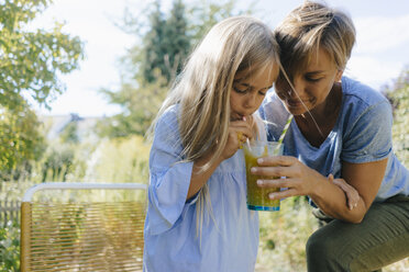 Mutter und Tochter trinken gemeinsam einen Smoothie im Garten - KNSF05090