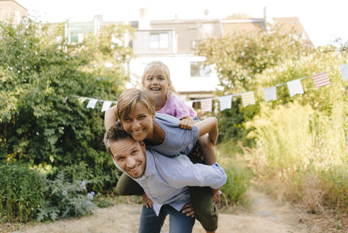 Happy father carrying family piggyback in garden - KNSF05108