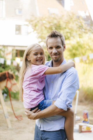 Porträt eines lächelnden Vaters mit Tochter im Garten, lizenzfreies Stockfoto