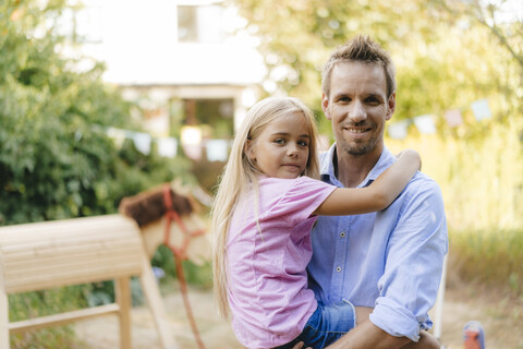 Porträt eines lächelnden Vaters mit Tochter im Garten, lizenzfreies Stockfoto