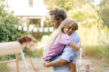 Father cuddling with daughter in garden - KNSF05126