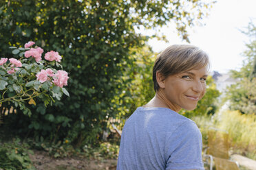 Porträt einer lächelnden Frau im Garten, die sich umdreht - KNSF05132