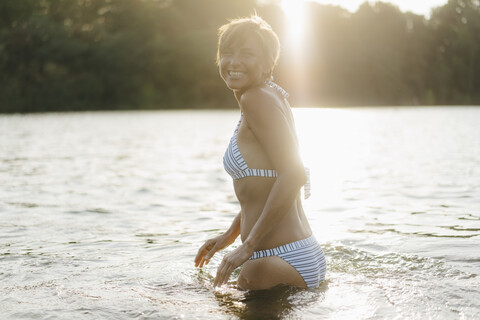 Portrait of happy woman wearing a bikini in a lake stock photo