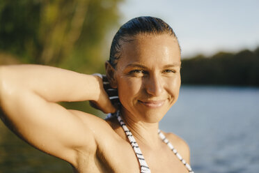 Portrait of smiling woman with wet hair at a lake - KNSF05159