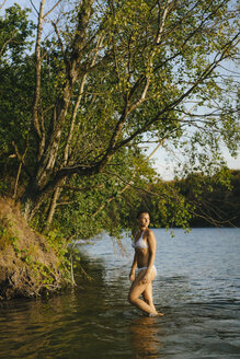 Frau im Bikini watet in einem See - KNSF05163