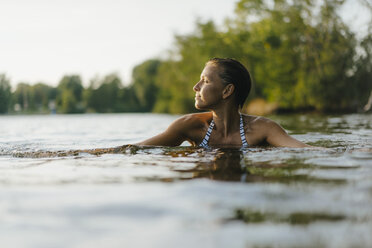 Frau schwimmt in einem See bei Sonnenuntergang - KNSF05164