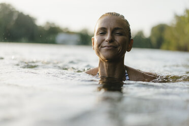Porträt einer lächelnden Frau beim Schwimmen in einem See - KNSF05166